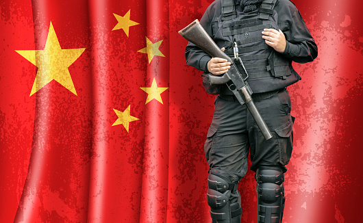 Policeman with weapon standing in front of chinese flag