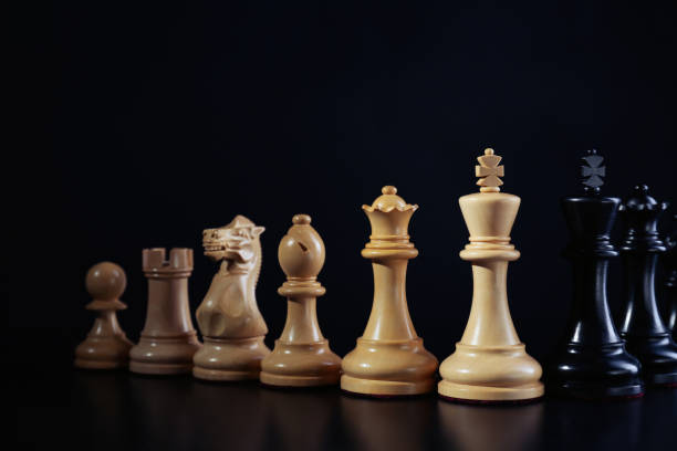 istock White and black chess pieces against dark background. Competition concept 1488253765