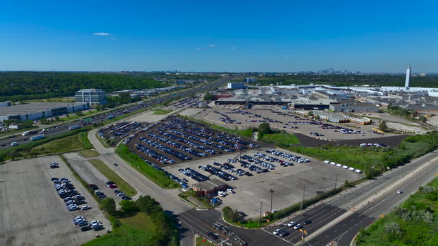 4K aerial footage of a car plant and new vehicles in a parking lot.