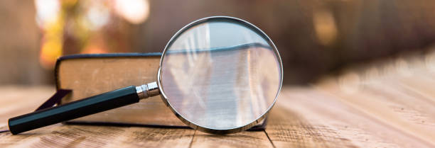 istock Book and magnifier on wooden table 1488255024