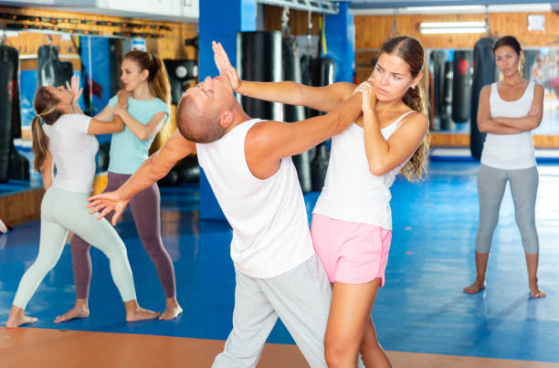 istock Young woman practicing palm heel strike to man in self-defense training in gym 1488257554