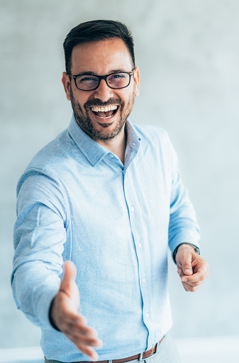 Portrait of smiling businessman offering handshake, standing with extended hand, friendly hr manager or team leader greeting or welcoming new worker or client. Businessman reaching out his hand for a handshake