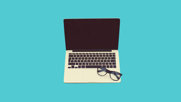 istock Close up laptop with blank black screen and eyeglasses on blue background 1488257656