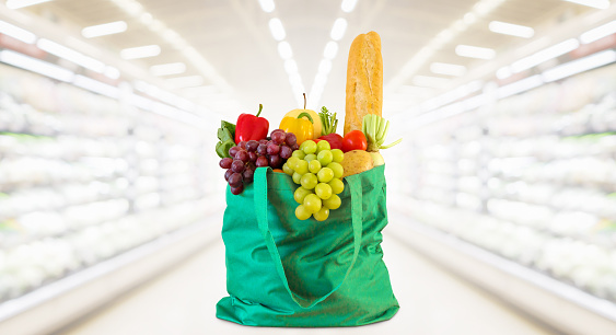 Shopping bag with fruits and vegetables in supermarket grocery store blurred background