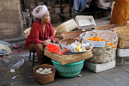 Ubud, Bali, Indonesia - September 5, 2019: Indonesian woman selling produce in a traditional open market on the streets of the popular tourist townn market on the streets of the popular tourist town