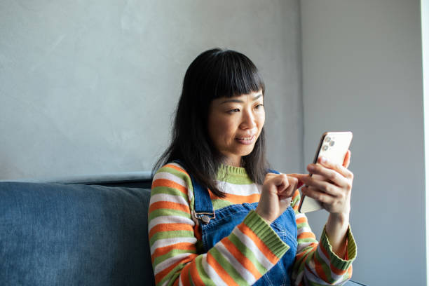 istock Young Japanese Woman using a smart phone at home 1488275589