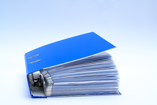 Blue office binder filled with paperwork, bureaucracy, isolated on white background