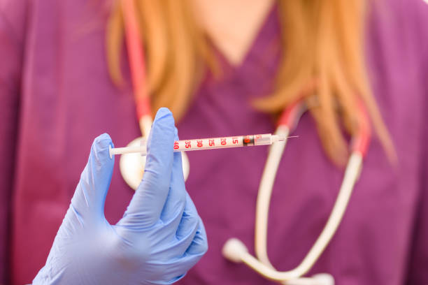 Female doctor holding a syringe for vaccination, injection in a blue glove