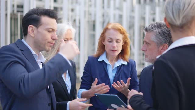 Worried business people looking the screen of a tablet outdoors