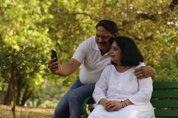 istock Happy Indian senior couple taking selfie while sitting on a park bench. 1488287640