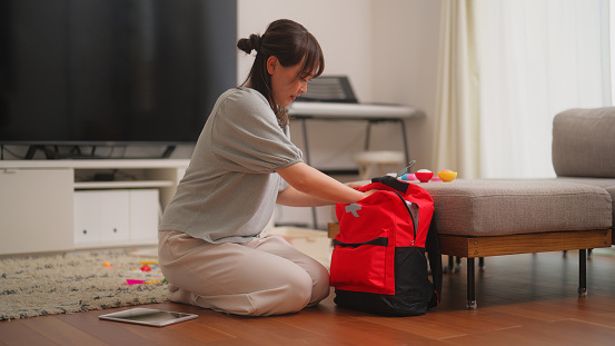 A woman is preparing an emergency bag in the living room at home.