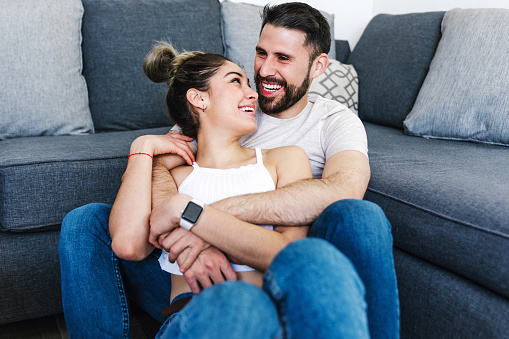young latin couple resting and having fun on sofa at home in Mexico, hispanic people in Latin America