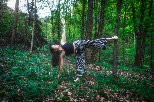 A girl practicing sports yoga in the nature in a forest