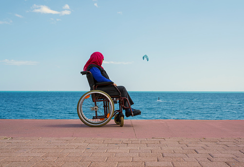 Senior woman on wheel chair strolling on the beach