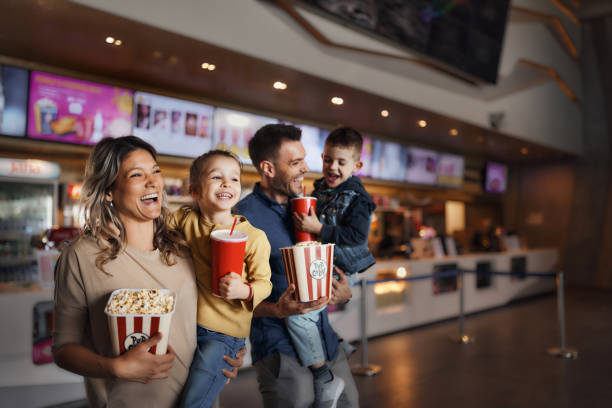 junge glückliche familie mit popcorn und getränken im kino. - film filmtechnik stock-fotos und bilder