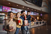 Young happy family with popcorn and drinks in movie theatre.
