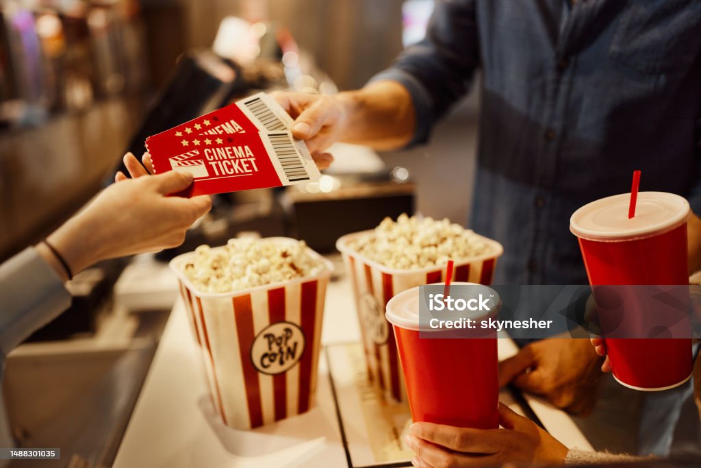 Buying movie tickets! Close up of unrecognizable cashier giving movie tickets to her customer in cinema. Movie Theater Stock Photo