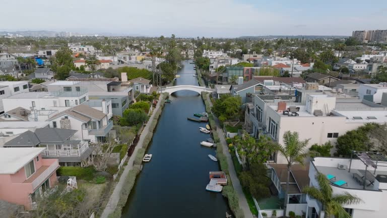 Fly above water canal surrounded by luxury family houses in residential urban borough. Venice neighbourhood. Los Angeles, California, USA