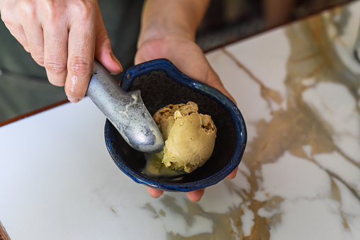 hand scooping a scoop of ice cream into a spoon in fridge