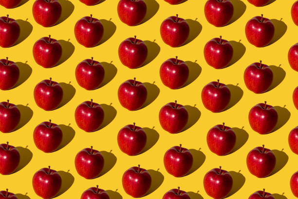 istock Trendy fruit pattern made of red apples on light yellow background. Minimal concept. 1488312925