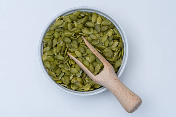 istock Green pitted pumpkin seeds in a round bowl on a white background 1488314389
