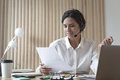 Young pleasant spanish businesswoman in headset with microphone during online meeting in office