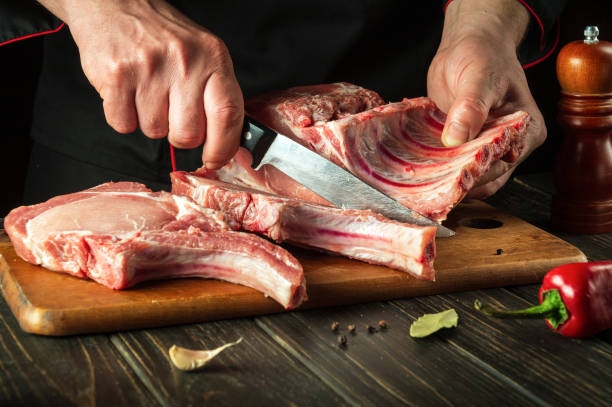 istock Chef cutting raw beef ribs with a sharp knife on wooden board. Process of cooking grilled bbq ribs. Asian cuisine. 1488320189