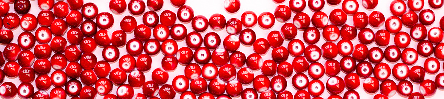 red handicraft items, jewelry, beads, DIY background. Plastic acrylic glass beads of different shapes and colors for making brooches, pendants, collars. Blur effect. Weak focus.