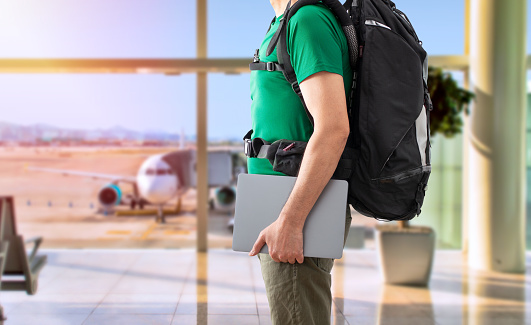 Close up of digital nomad man traveling the world working with his laptop at airport