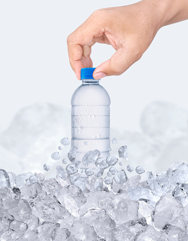 A man hand with bottle of water passing through ice cubes