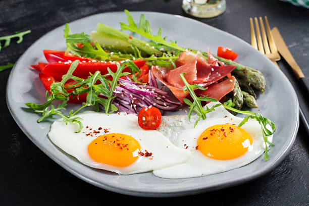 istock Keto breakfast. Fried asparagus with roasted eggs and  prosciutto or jamon. Ketogenic diet. Healthy food. 1488331292