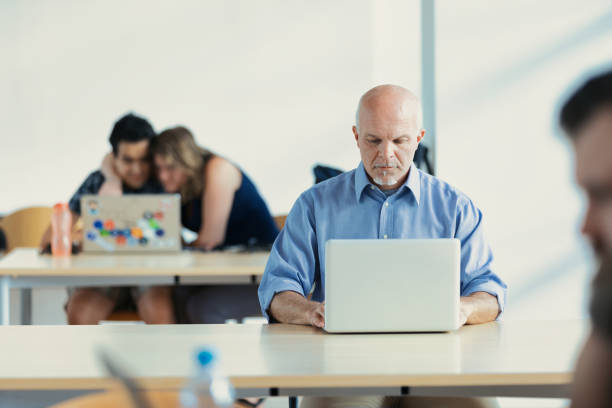 istock Mature man with laptop in library 1488333748