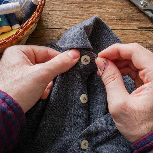 istock man sews a button to his shirt 1488334013
