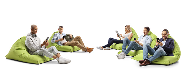 Young people sitting on a bean bag armchairs and using smartphones isolated on white background
