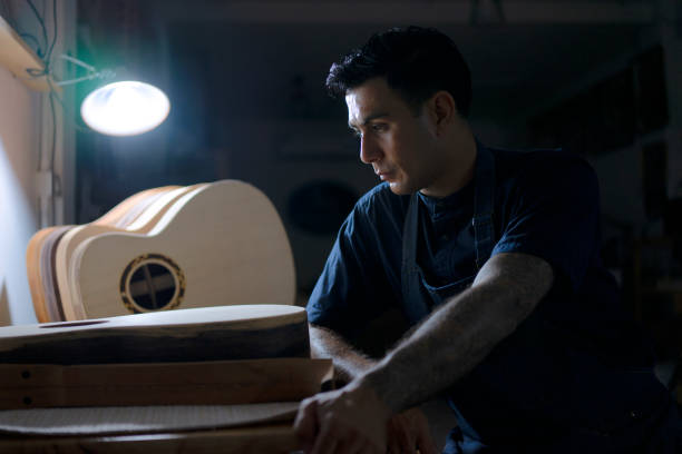 Guitar maker is making guitar at workshop. Guitar maker is making guitar at workshop. Custom guitar and small business concept. acoustic guitar tattoos stock pictures, royalty-free photos & images