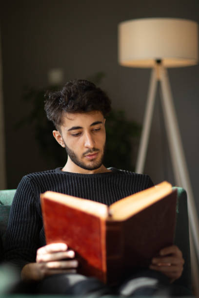 istock Young man relaxing with a book on his sofa at hom 1488339778