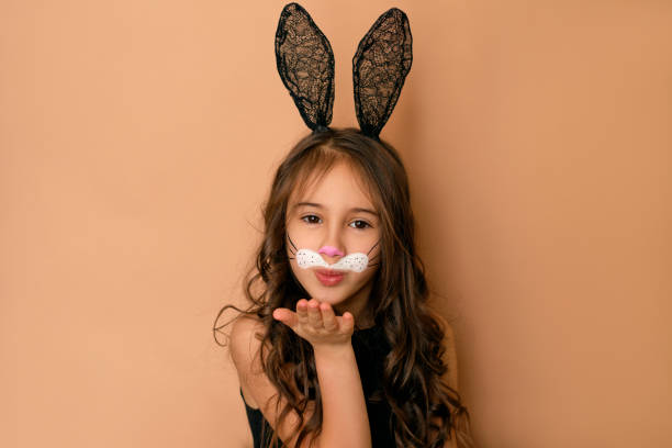 красивая милая девушка-модель, одетая как пасхальный кролик, посылает воздушный поцелуй - face paint child paint rabbit стоковые фото и изображения