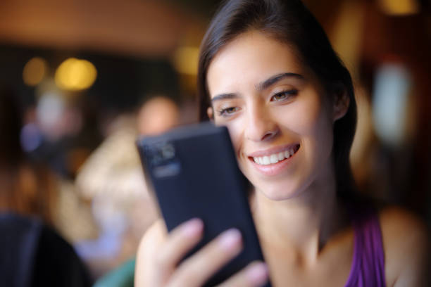 istock Happy woman in a restaurant using phone 1488341348