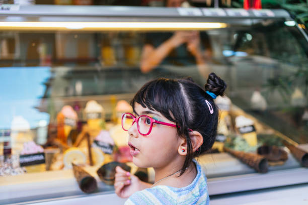 Girl with glasses choosing an ice cream in an ice cream shop. stock photo