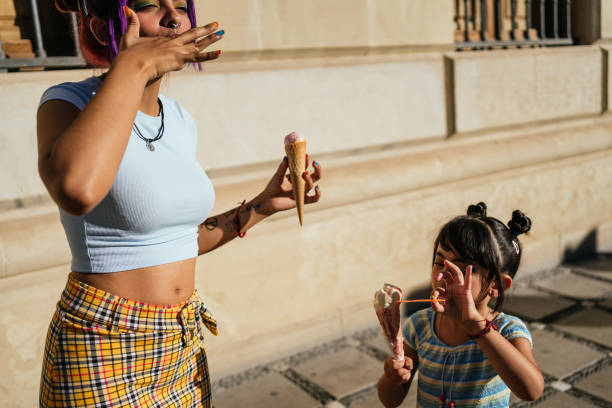 Girl with her mother eating an ice cream in the street. stock photo