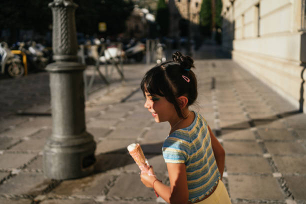 Child running around in the street with an ice cream in her hands stock photo