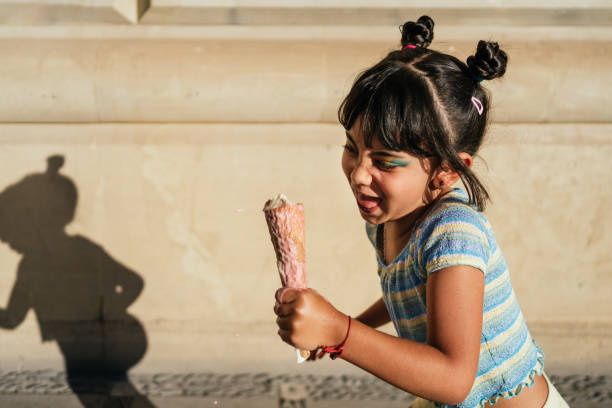 Child running with an ice cream in her hand. stock photo