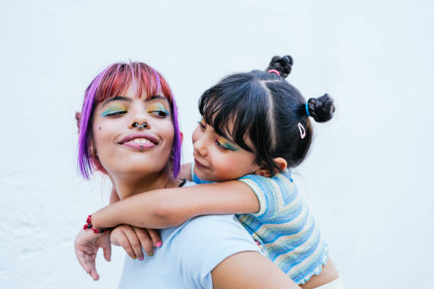 A little girl playing on her mother's shoulders looking at each other. stock photo