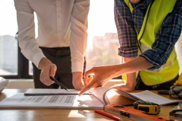 istock Focused at the desk. behind is engineer and construction team leaders work together. View house designs and renovate plans. Construction projects. Mortgage, rent, buy, sell, move houses. 1488344018