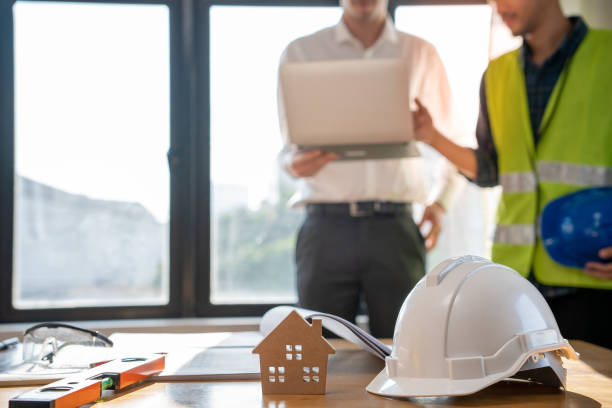 istock Focused at the desk. behind is engineer and construction team leaders work together. View house designs and renovate plans. Construction projects. Mortgage, rent, buy, sell, move houses. 1488344078