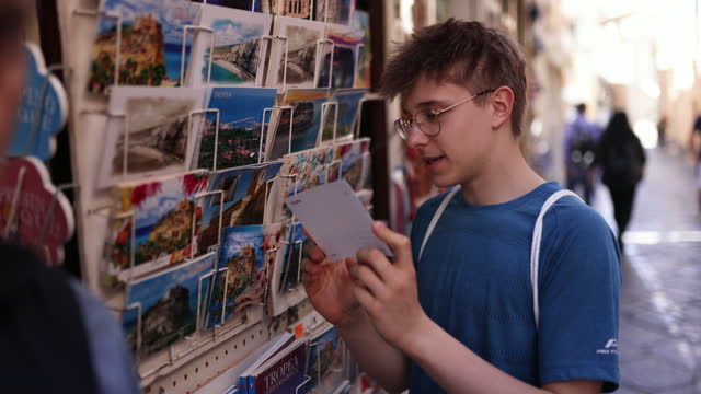 Teenage boy browsing postcards at street stand