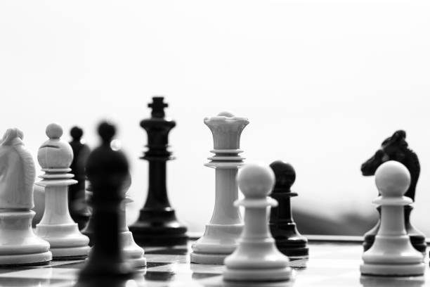 ゲームの白い背景にボード上のチェスの駒の女王と王。女王が王を攻撃することに焦点を当てたボード上のチェスの駒。黒と白のチェスの駒はスペースをコピーします - chess king chess chess piece black ストックフォトと画像