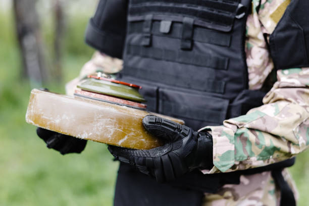 A man in a special suit works with a detector and found an explosive device. A man tries to neutralize an anti-tank mine.