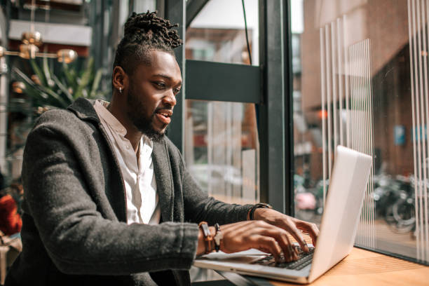Handsome black adult student using AI A.I. on a laptop computer stock photo