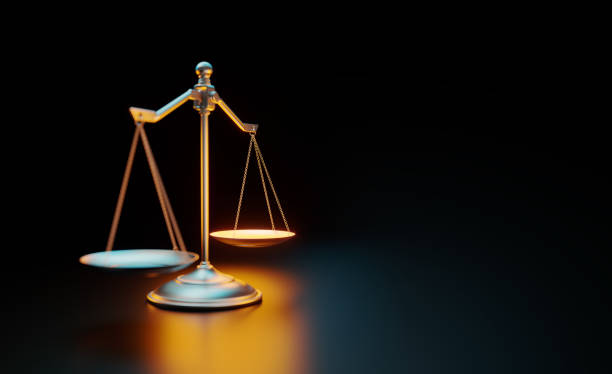 mosiężna skala oświetlona żółtymi i niebieskimi światłami na czarnym tle - legal system scales of justice justice weight scale zdjęcia i obrazy z banku zdjęć